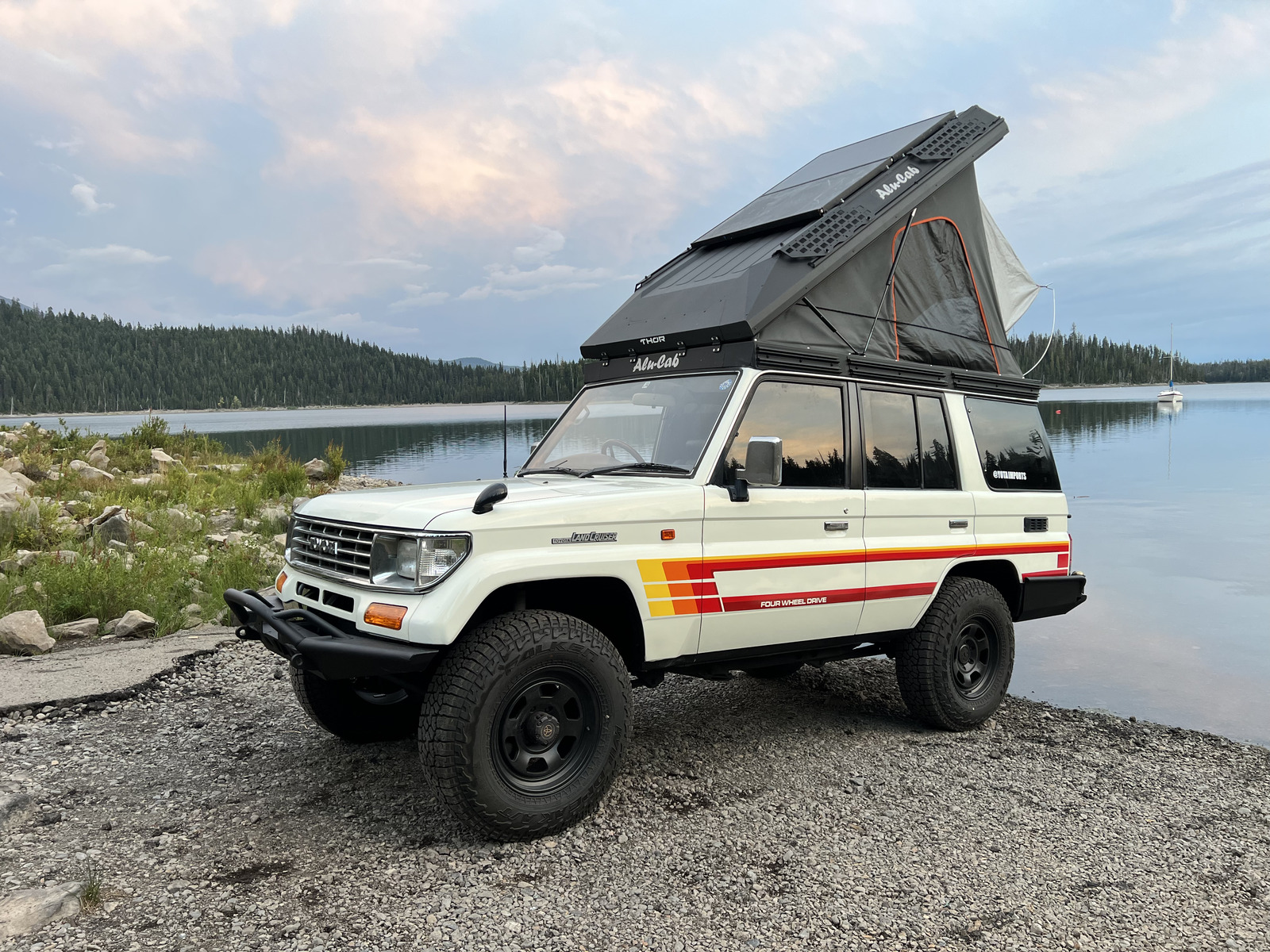Prado Land Cruiser camper with pop-up roof tent at a lake