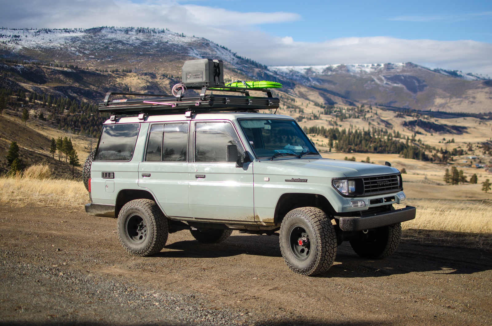 Mint green Prado Land Cruiser with kayak on roof rack in the mountains